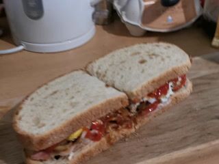 Breakfast egg and bacon sandwich with mushrooms and ketchup on toast. Also roast and ground coffee